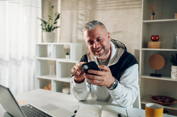 Middle aged man using a smartphone while working in a home office