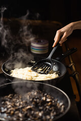 Frying mushrooms in a pan. Finely chopped champignons are cooked. Steam is coming.