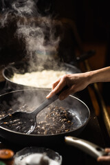 Frying mushrooms in a pan. Finely chopped champignons are cooked. Steam is coming.