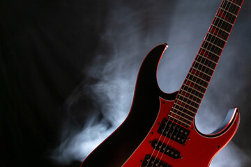 Music concept. Electric guitar isolated on a dark background under beam of light with smoke