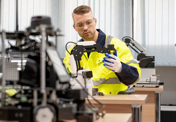 Computer science development engineer working on robotic arm connection and control at electronic futuristic technology center. Modern people training in industry 4.0 automated engineering workshop