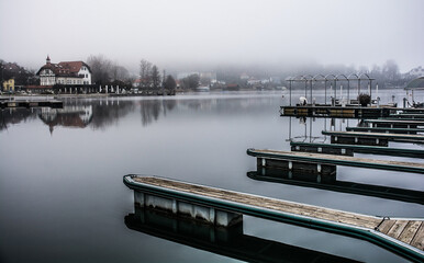 Boat jetties on a foggy winter day at Reifnitz am Worthersee on the south shore of Worthersee, or Worth Lake, in Carinthia, Austria
