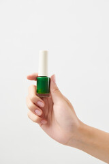 녹색 메니큐어를 들고 있는 여성의 손