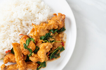 stir-fried fried fish with basil and chili in thai style topped on rice
