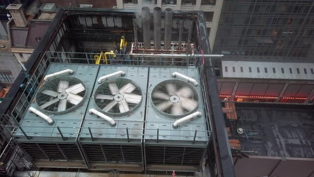 Rooftop air conditioning unit in New York with rotating propelliers and steam from heating pipes, slow motion
