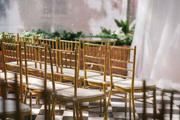 Close up fo the golden Tiffany chairs in the indoor farden wedding setup .
