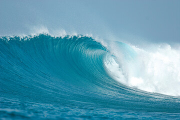 A perfect blue wave breaks in the ocean in the Maldives Islands.
