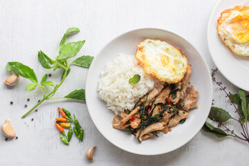 Stir fried basil with pork and fried egg has rice on white table top view.