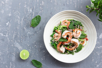 Healthy food shrimp salad has peppermint lemon grass kale in bowl on grey wood background.