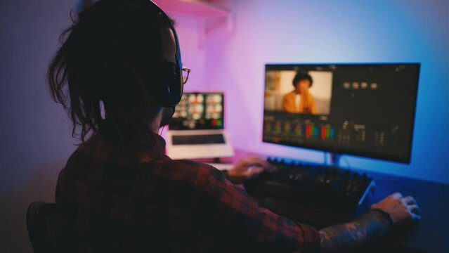Young man in glasses working on video editing on computer doing montage and color correction. Professional man hand making edits on a special panel. Concept of creating video content.