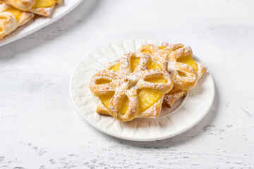 Baked pineapples in puff pastry sprinkled with powdered sugar on a light blue background, top view. Delicious homemade puffs