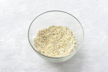 Glass bowl with cheese mixed with flour and herbs on a light gray background. Cooking delicious homemade gnocchi