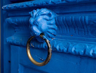 Blue doorknob in the form of a lion's head with a ring  on a wooden ornament