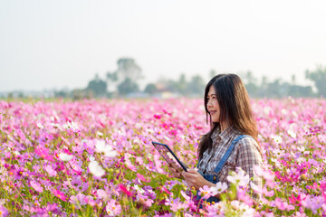 Happy woman farmer owner holding tablet at flower farm for modern farming, technology,smart woman, flower business idea concept.