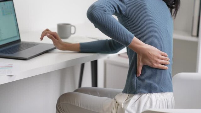 Young Asian business woman suffering from back pain while working. Office syndrome concept.