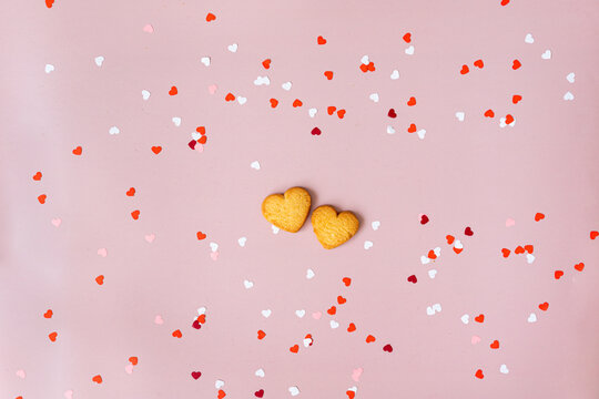 the mood of valentine's day, on a pink background in the center are two heart-shaped cookies