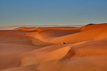 Fototapeta na wymiar sand dunes and car driving in the desert