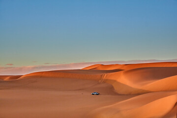 Fototapeta na wymiar View of Sands dunes and car driving in the desert of Algeria 