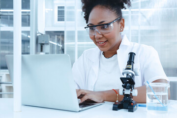 smiling black scientist doctor student studying and experiment analysis test sample with writing report in computer. ambitious young biotechnology Specialist. medical science laboratory education.