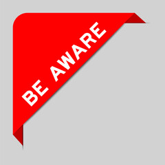 Red color of corner label banner with word be aware on gray background