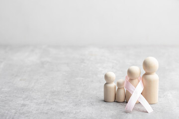 Family wooden figure and pink ribbon. Cancer treatment concept.
