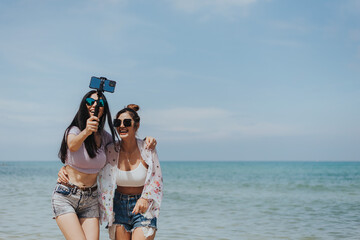 Happiness woman and friends having fun and enjoyment on summer beach. teenagers female record Vlog video with smartphone and laughing together at tropical beach on weekend. friendship and freedom.