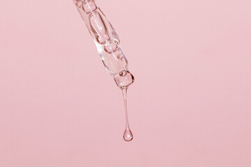 Cosmetic pipette with dripping liquid and drops on a pink background, serum, serum, gel, vitamin, water, oil - obrazy, fototapety, plakaty