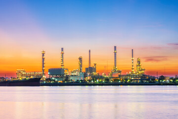 Obraz na płótnie Canvas Panorama of oil refinery with reflection, petrochemical plant.Gas refinery beside river.Colorful twilight at sunrise time.Slow speed shutter made motion blur.Water pollution from industry may concern.