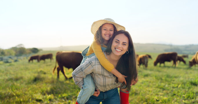 Family, farm and fun with a girl and mother playing on a grass meadow or field with cattle in the background. Agriculture, sustainability and love with a woman and her daughter enjoying time together