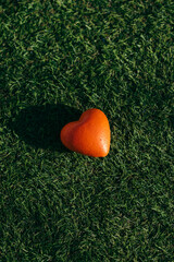 red heart lies on green grass.