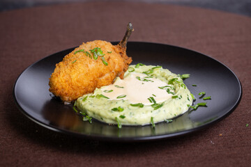 Kiev cutlet with mashed potatoes on a black plate