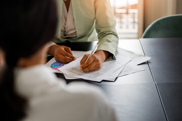 Business coworkers with documents at the office. Afro-American woman signing a document at the office 