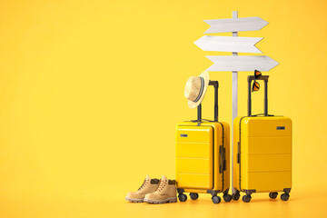 Yellow suitcases with travel assessories and signpost on yellow background. Travel and tourism direction concept background.
