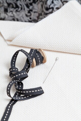 Black ribbon wound on wooden spool on white fabric..