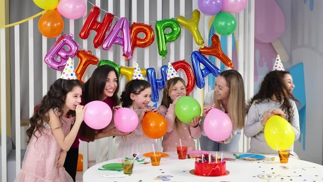 Group of children celebrate a children's birthday, have fun. Children and parents inflate balloons.