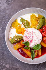 Salad with buratta cheese and tomatoes with pesto sauce in a bowl top view