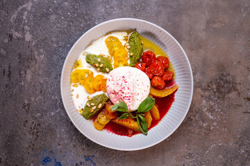 Salad with buratta cheese and tomatoes with pesto sauce in a bowl top view