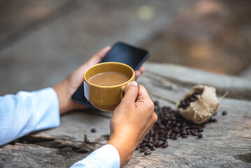 Asian man holding hot coffee in paper mug cup to sniff smell of espresso in morning sunlight. man carry coffee break to sniff fragrant smell the aroma of coffee and work.