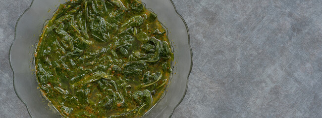 Soft focus cassava leaf vegetable curry served with a mixture of Indonesian spices.