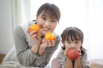 りんごとみかんを持つ親子