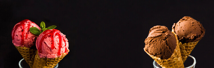 Chocolate and strawberry ice cream in the waffle cone on the black background. Copy space. Banner.