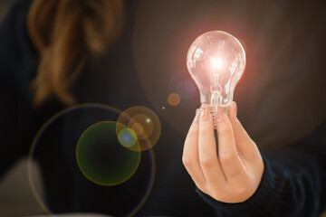 Woman holding a light bulb in her hand.