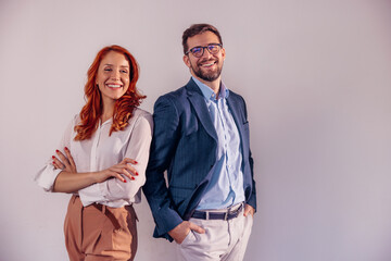 Business partners posing in front of gray background, looking at camera and smiling. - Powered by Adobe