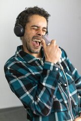 Mixed race man dressed in checked shirt singing into a condenser microphone