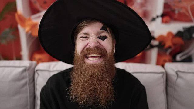 Young redhead man wearing wizard costume having halloween party at home