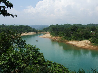 The boat, the green water river, and the hills of Lalakhal,  a popular tourist destination in Sylhet Bangladesh.