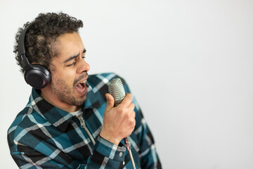 Mixed race man dressed in checked shirt singing into a condenser microphone