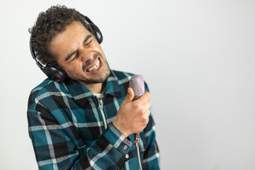 Mixed race man dressed in checked shirt singing into a condenser microphone
