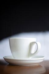White cup hot drinking with steam on pine wooden table

