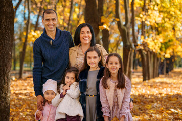 Fototapeta premium portrait of big family in autumn city park, children and parents, happy people posing together, beautiful nature, bright sunny day and yellow leaves